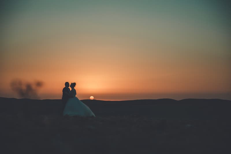 des mariés s’embrassant lors d’un coucher de soleil dans le désert de Marrakech