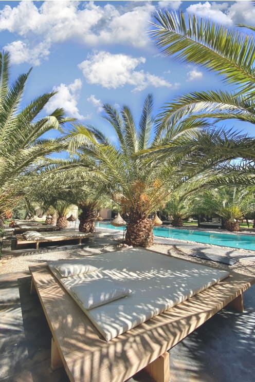 des lits exterieurs au bord de la piscine et les plamiers chez la villa taj marrakech