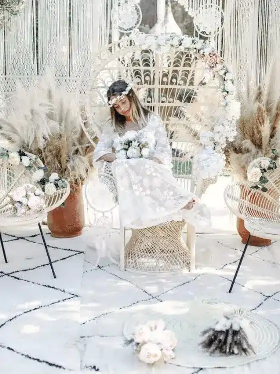 Jeune demoiselle en robe bohème chic blanche assise sur une chaise en osier chez Villa Taj